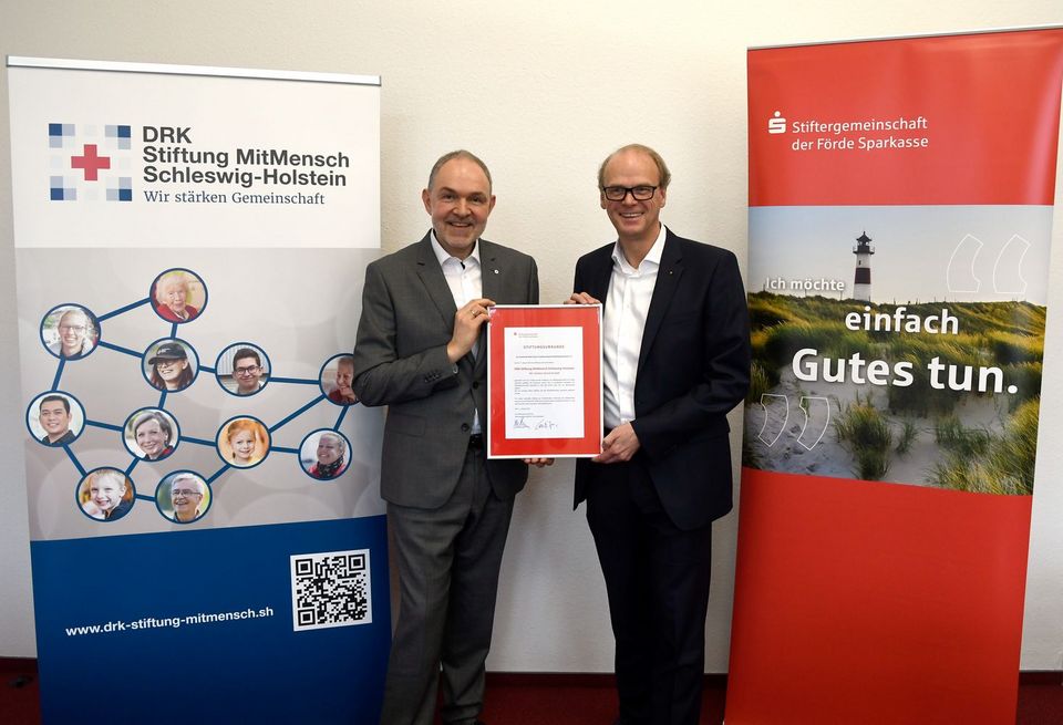 Ralph Schmieder (DRK) und Carsten Zarp (Förde Sparkasse) stehen nebeneinander und halten gemeinsam eine Urkunde in den Händen.